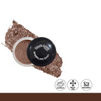 Open container of sparkling dust with a black lid, surrounded by scattered glitter on a white background.