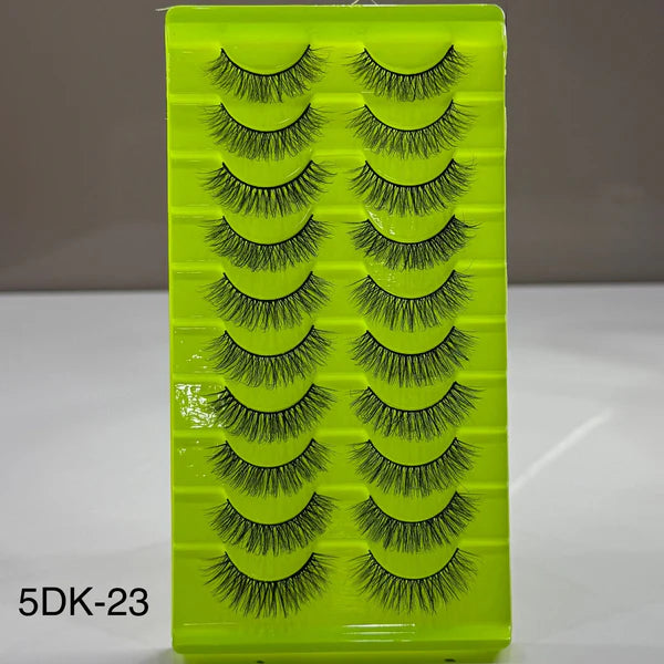 Set of false eyelashes on a green tray with a gray background