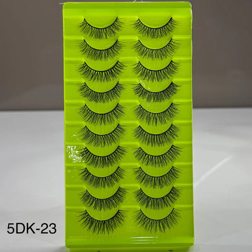 Set of false eyelashes on a green tray with a gray background