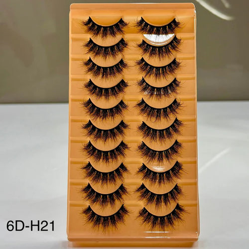 Set of false eyelashes in a wooden display box on a white surface.