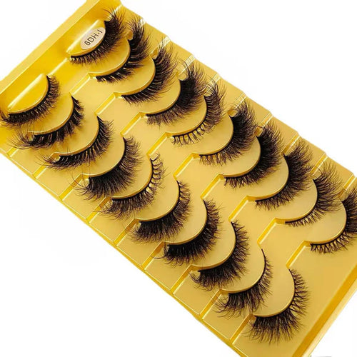 Set of false eyelashes on a yellow tray with a white background