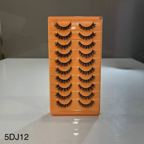 Set of false eyelashes in an orange holder on a white surface