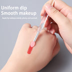 Hand applying red lip makeup with a brush on a gray background
