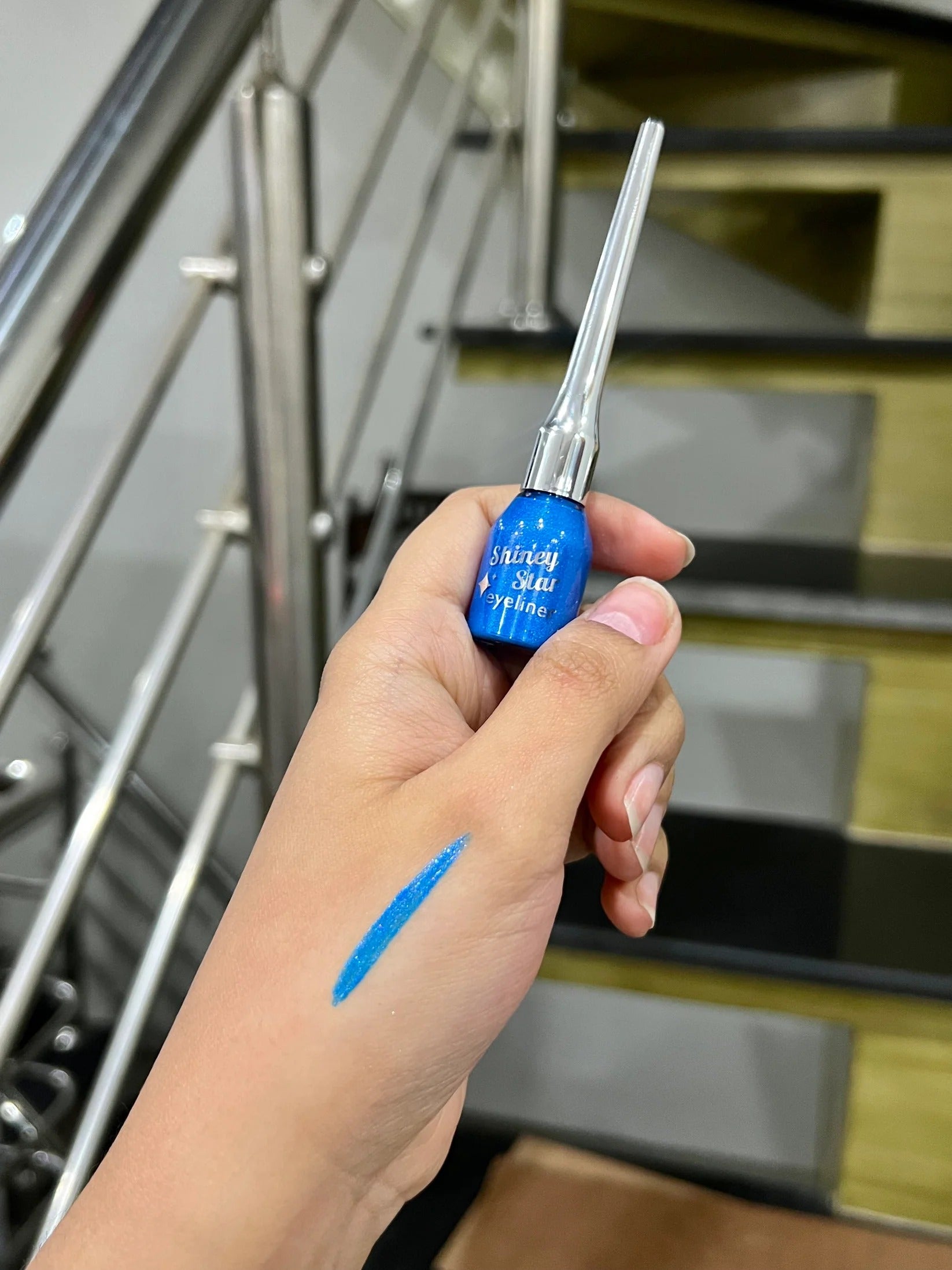 Hand holding a blue marker with a blurred staircase background