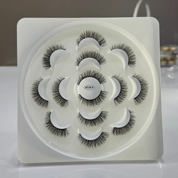 Set of false eyelashes in a decorative white tray on a light gray background