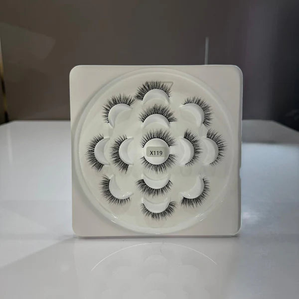 Set of false eyelashes in a white square container on a white surface.