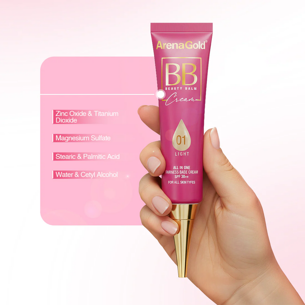 Hand holding a pink tube of ArenaGold BB Beauty Balm Cream against a light pink background