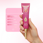 Hand holding a pink tube of ArenaGold BB Beauty Balm Cream against a light pink background