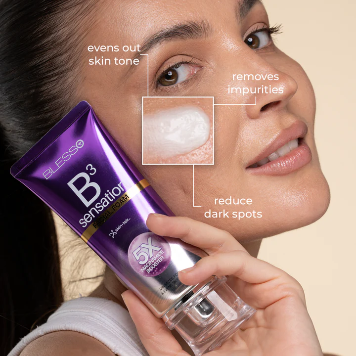 A woman holds a purple Blesso B3 Sensation niacinamide facewash tube next to her face, with text callouts explaining skin benefits. The tube is purple with white and gold lettering, and the woman's face is shown in a close-up against a light beige background.