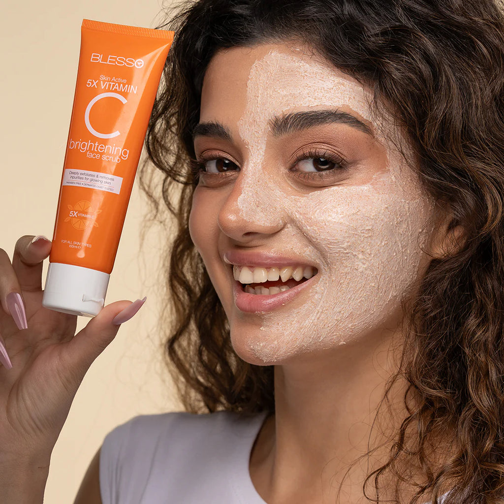 Woman with a face mask applying Blesso brightening face scrub