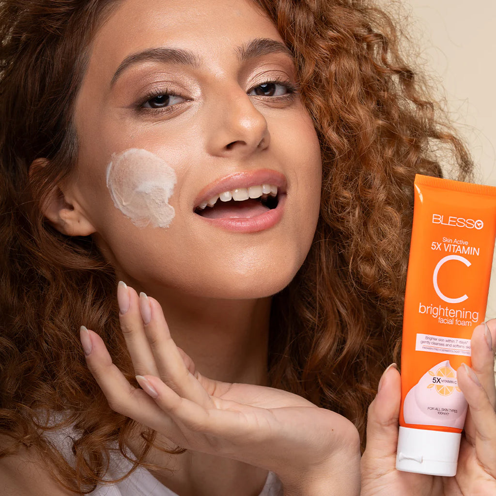 Woman applying sunscreen cream to her face with a tube of Blesso Vitamin C brightening cream.