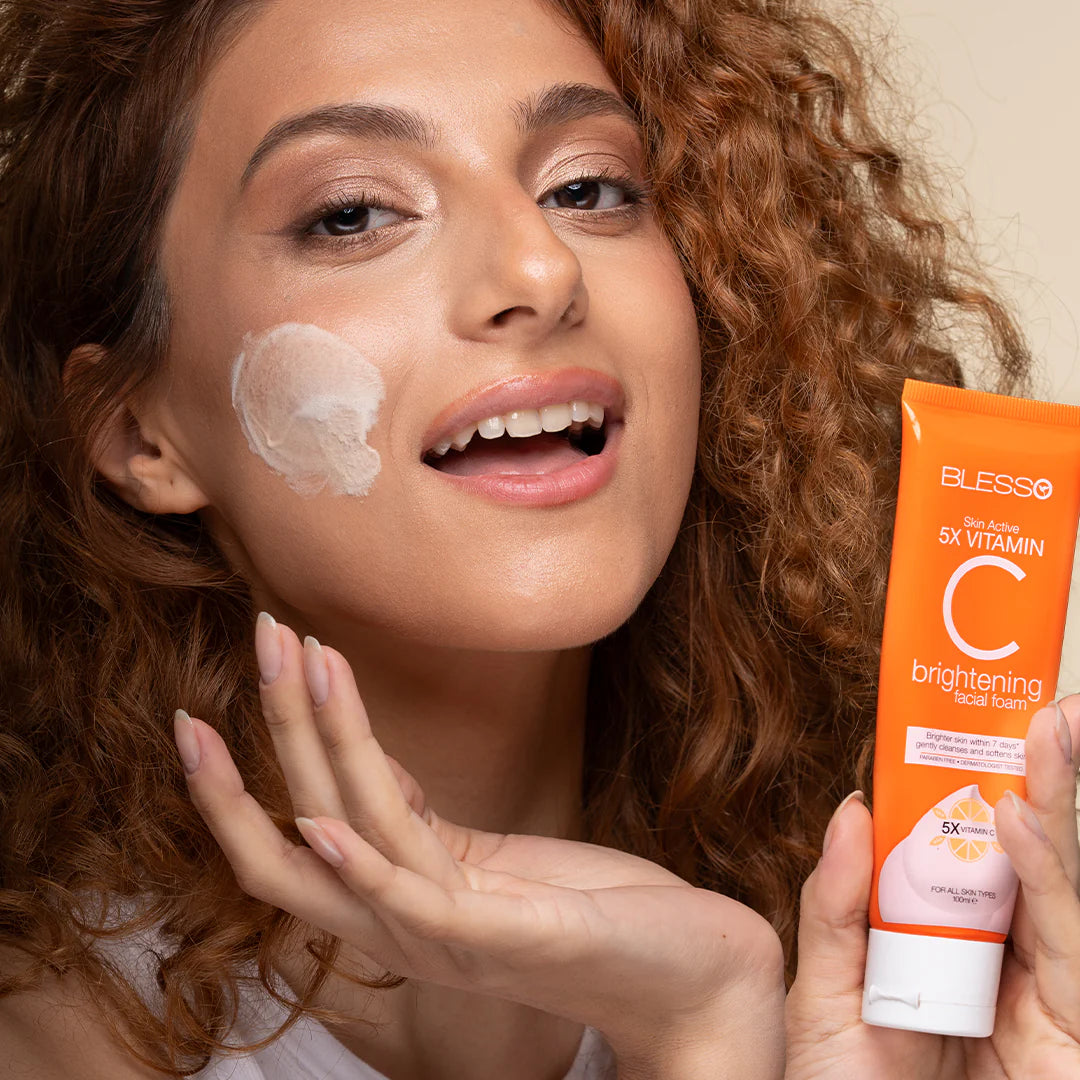 Woman applying sunscreen cream to her face with a tube of Blesso Vitamin C brightening cream.