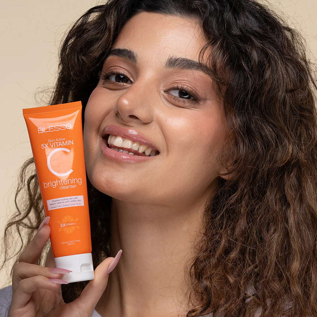 Woman holding an orange skincare Blesso product with visible branding
