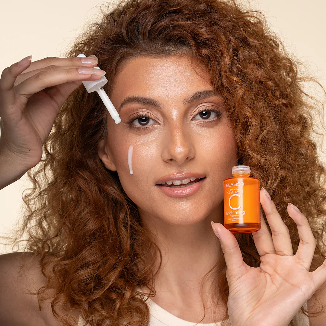 Woman applying a skincare Blesso product to her face with a bottle in hand