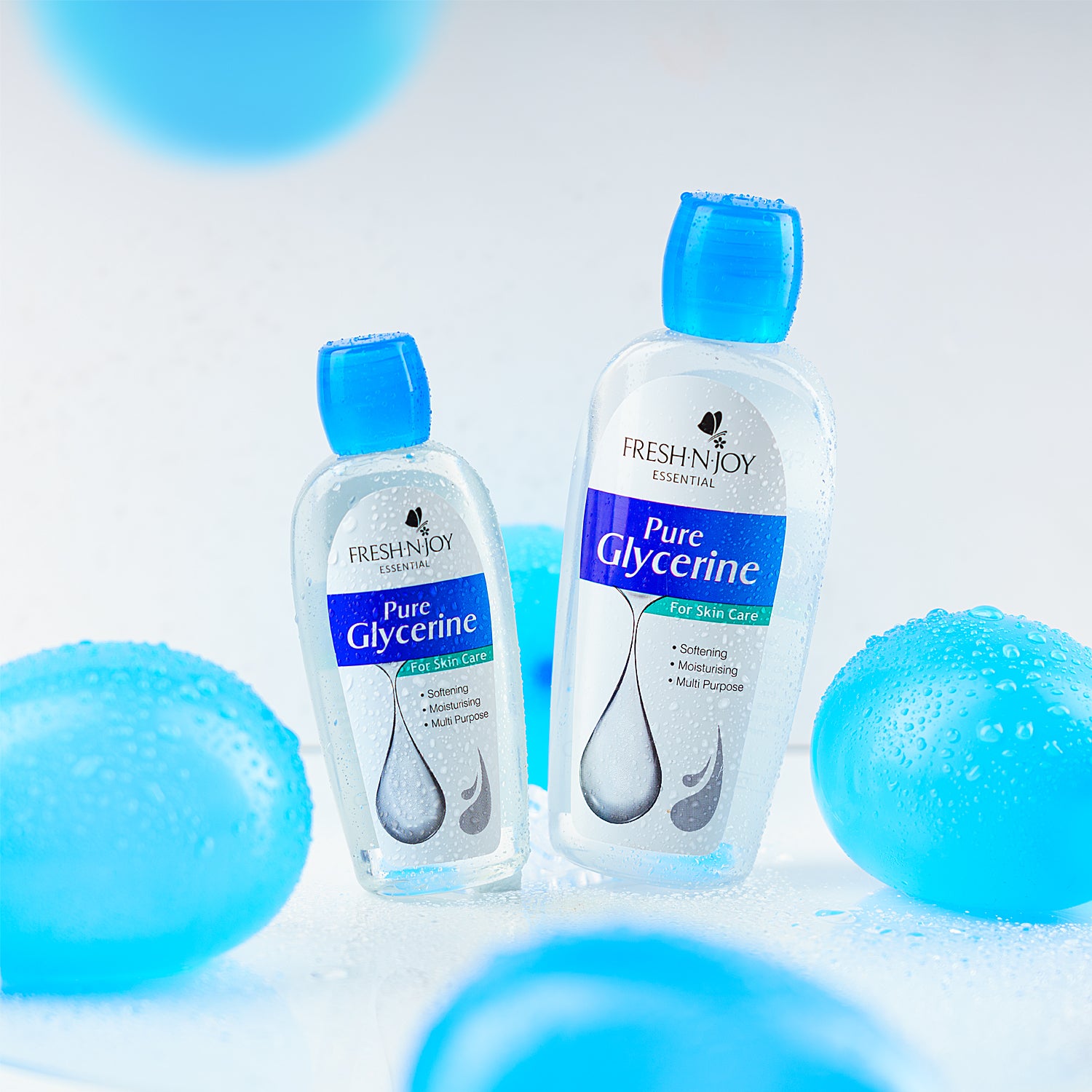 Two bottles of FreshnJoy Pure Glycerine on a light blue background with blue spherical objects.