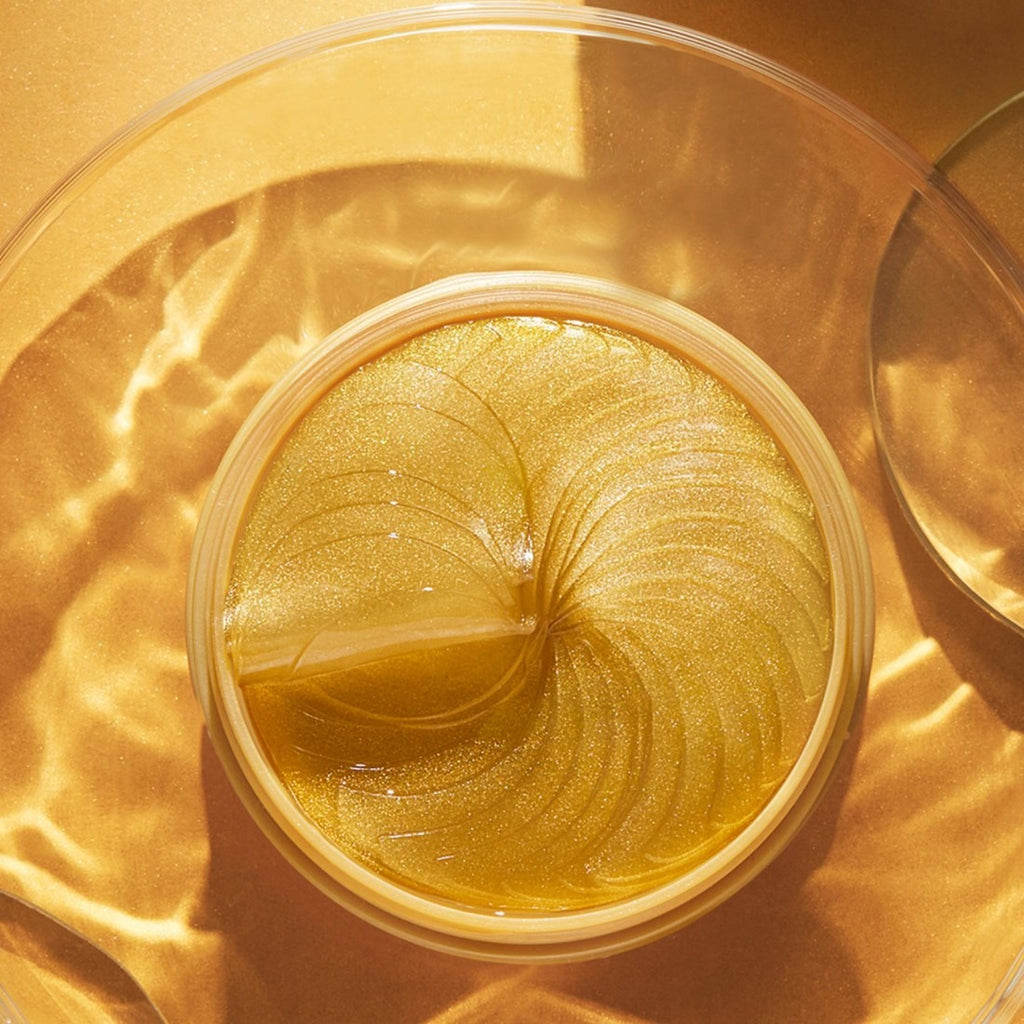 Gold-colored cosmetic cream in a jar on a gold background