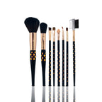 Set of makeup brushes with black handles and gold accents on a white background