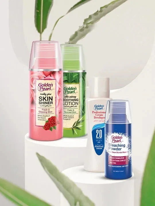 Collection of Golden Pearl skincare products on a white surface with green leaves in the background
