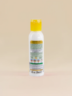 Bottle of Golden Girl Cleansing Milk with a yellow cap on a beige background