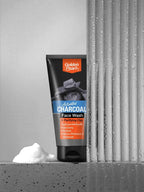 Tube of Golden Pearls Activated Charcoal Face Wash with a block of soap on a concrete surface.
