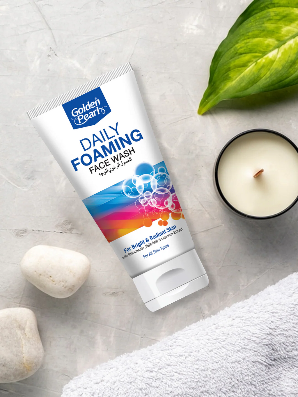 Tube of Golden Pearls Daily Foaming Face Wash on a light gray surface with a candle and leaves.