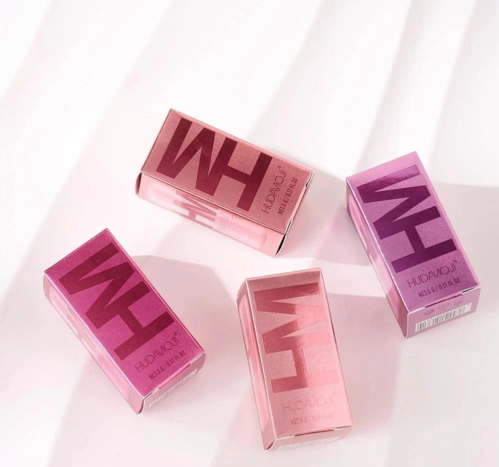 Four pink and purple makeup products with 'HUDAMOJI' branding on a white background