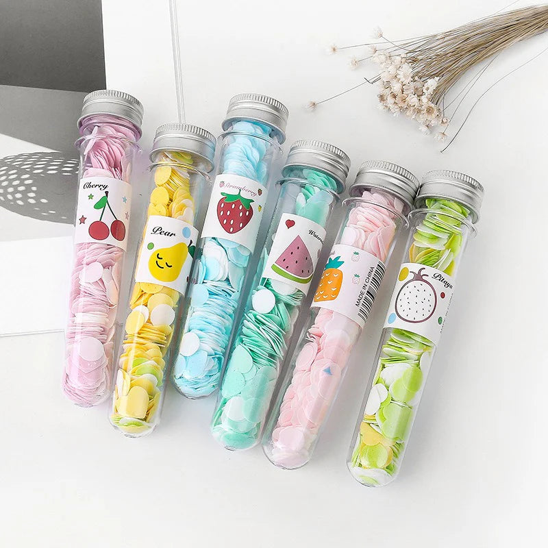 Colorful candy in transparent tubes with labeled designs on a white surface.