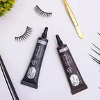 Two tubes of lash glue with false eyelashes on a white surface