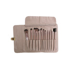 Set of makeup brushes in a beige holder on a white background