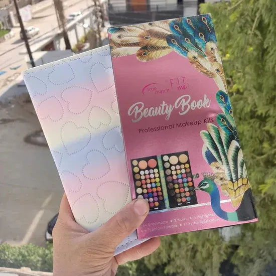 Hand holding a pink makeup kit packaging with peacock design outdoors.