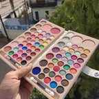 Makeup palette with colorful eyeshadows held by a hand outdoors.