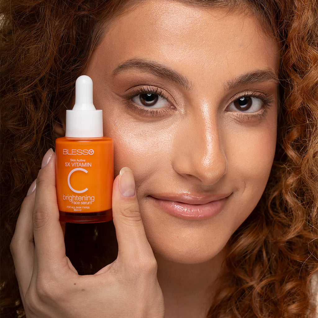 Woman holding a bottle of Blesso Vitamin C serum close to her face